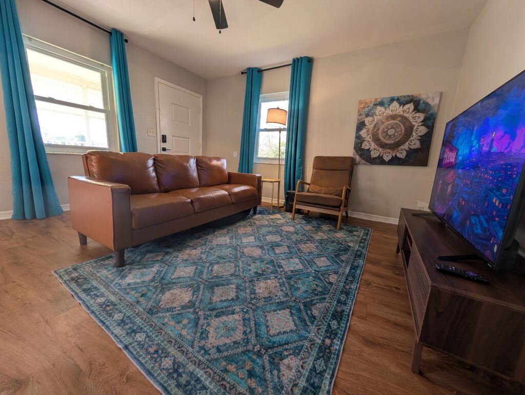 Brown sofa, turquoise curtains and television at the two-bedroom Murray Hill cottage